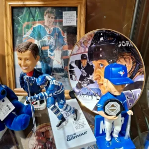 Sports memorabilia display featuring a signed Wayne Gretzky Oilers photo, a Doug Gilmour figurine, and Toronto Blue Jays collectibles.