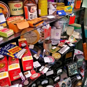 Glass display case filled with vintage automotive tins, hardware supplies, and retro shop collectibles.