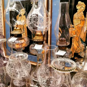 Collection of vintage clear glass oil lamps with ornate brass burners and etched glass chimneys.