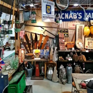 Industrial-style display featuring vintage wooden oars, metal milk jugs, lanterns, and old Canadian license plates.