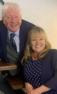 Henry Jones in a sharp suit and tie posing with Jackie for a formal occasion.
