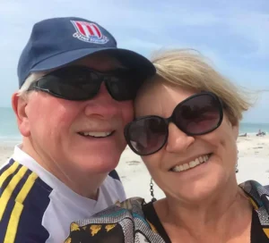 Henry Jones and Jackie wearing sunglasses on a sunny beach day.