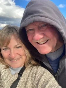 A cozy close-up selfie of Henry Jones in a hoodie and Jackie in a warm sweater outdoors.