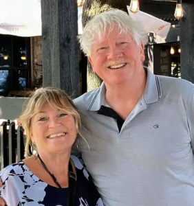 Henry Jones and Jackie enjoying a sunny day at an outdoor patio with string lights in the background.