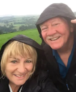 Henry Jones and Jackie wearing rain hoods while exploring green hills in the countryside.