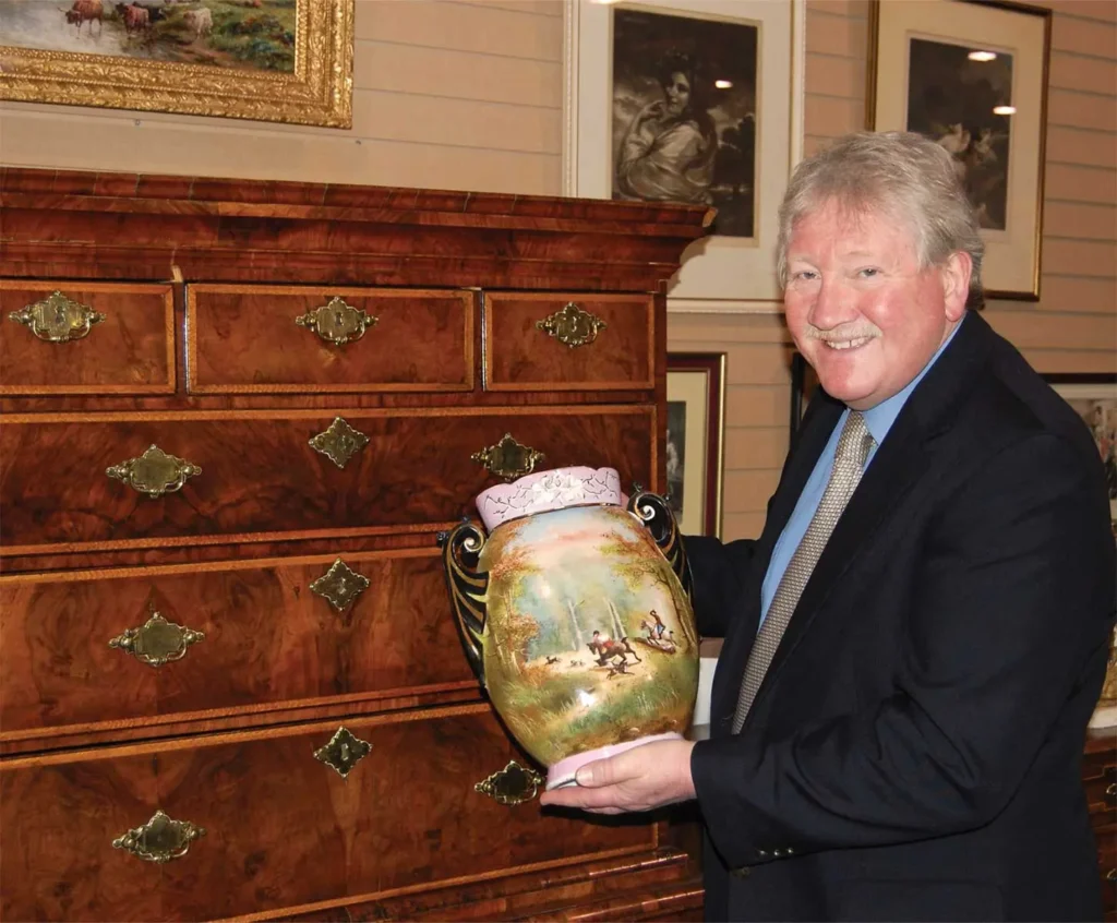 Henry Jones, founder of Roadshow's 400 Antiques Mall, in the showroom with an antique hand-painted vase