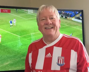 Henry Jones proudly wearing his Stoke City FC jersey while watching a soccer match on TV.