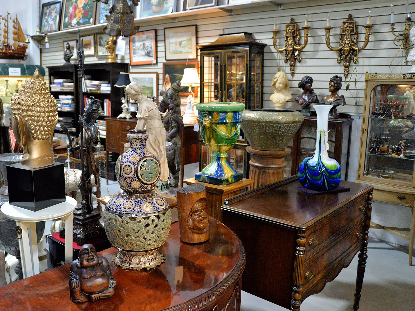 Interior of Roadshow Antiques Mall showroom displaying a diverse collection of antiques including ceramic vases, bronze sculptures, fine art, furniture, and decorative objects